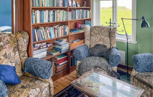 uma sala de estar com duas cadeiras e uma estante de livros com livros em Cozy Home In Sankt Ibb With Kitchen em Sankt Ibb