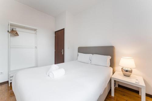 una camera con un grande letto bianco e una lampada di GuestReady - Modern Duplex, Neo-Classical Building a Porto