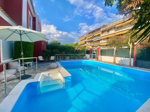 a swimming pool with an umbrella next to a building at Corfu Dream Holidays Villas Kanoni in Kanoni