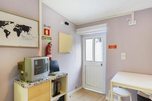 um quarto com uma televisão, uma secretária e uma porta em GuestReady - An amazing stay in Heroismo no Porto