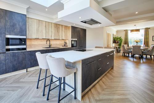 a kitchen with wooden cabinets and white counter stools at Host & Stay - Finch House in Stokesley