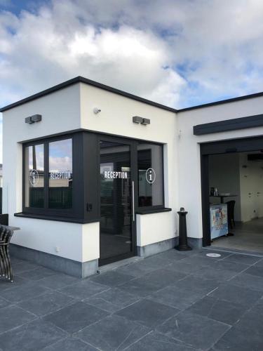 a white building with glass doors on a patio at Camping Oasis Middelkerke Romy 1, 2, 3, 4 in Ostend