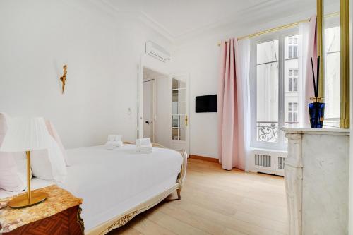 une chambre blanche avec un lit blanc et une fenêtre dans l'établissement Pick A Flat's Apartment in République - Avenue de la République, à Paris