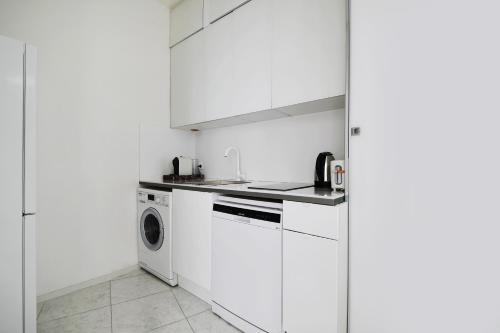 une cuisine avec des armoires blanches et une machine à laver dans l'établissement Pick A Flat's Apartment in République - Avenue de la République, à Paris