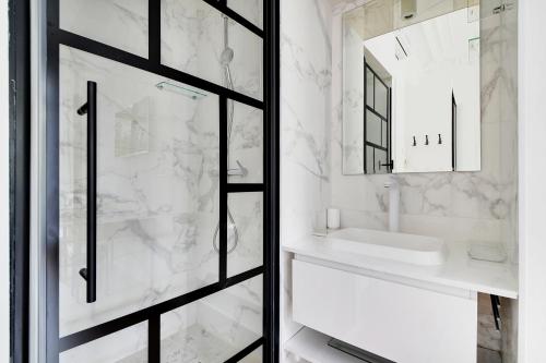 La salle de bains est pourvue d'un lavabo et d'une porte de douche en verre. dans l'établissement Pick A Flat's Apartment in République - Avenue de la République, à Paris