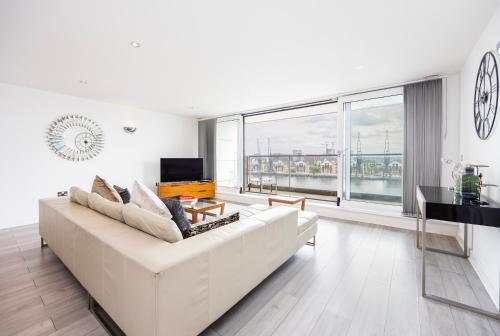 a white living room with a white couch and a piano at Austin David Executive ExCeL in London