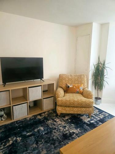 a living room with a chair and a flat screen tv at Seaside Haven Coastal Comfort 200m from the Beach in Kent