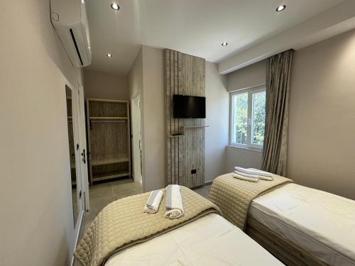 a bedroom with two beds and a tv and a window at Hotel Kseal in Përmet