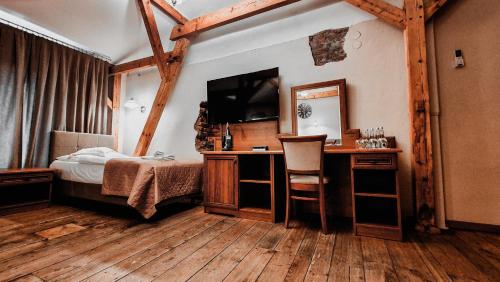 1 dormitorio con 1 cama y escritorio con TV en Hotel Zamkowy Młyn, en Krapkowice