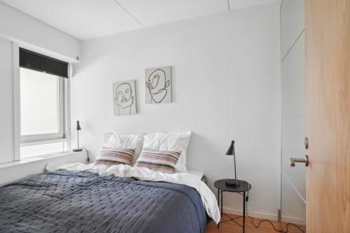 een witte slaapkamer met een bed met 2 kussens bij Skovnær Idyl: Charmerende 1BR Oase i Risskov in Risskov