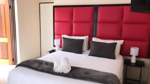 a bedroom with a large bed with a red headboard at Dineo's Lodge and Spa in Burgersfort