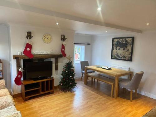 a living room with a table and a christmas tree at Cosy Cottage in the Norfolk Countryside in Whissonsett