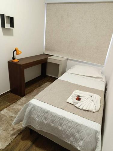a small bedroom with a bed and a desk at Residencial Luce Del Sole - Casa Nº 6 in Joinville