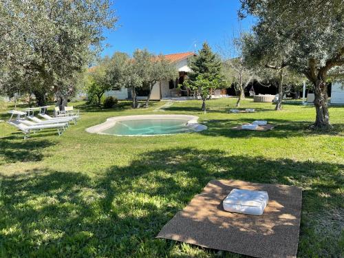 una pequeña piscina en un campo con bancos y árboles en Villa Acquabella, en Ortona