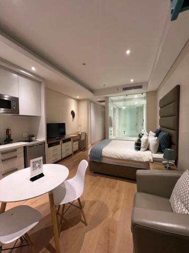 een slaapkamer met een bed, een tafel en een bank bij Sandton Skye Apartment in Johannesburg