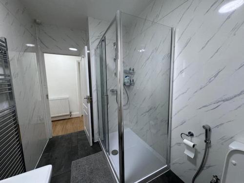 a bathroom with a shower with a glass door at Elegant living, 3 bedroom modern house in London