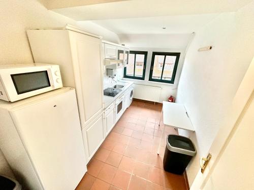 eine Küche mit weißen Schränken und einer Mikrowelle in der Unterkunft Moderne Location für 12 Gäste in Top-City-Lage in Wolfsburg