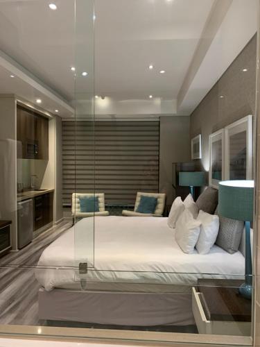 een slaapkamer met een groot bed en een glazen wand bij Sandton Skye Apartment in Johannesburg