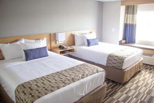 a hotel room with two beds and a window at Microtel Inn & Suites by Wyndham Camp Lejeune/Jacksonville in Jacksonville