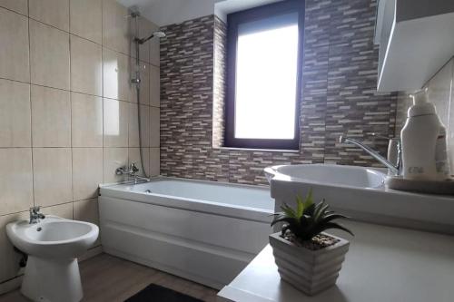 a bathroom with a tub and a toilet and a sink at MountainView Home in Codlea