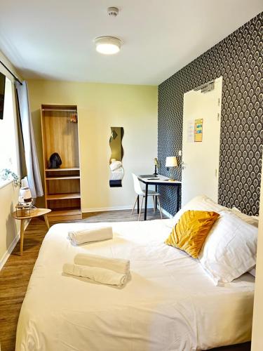 a large white bed in a room with a table at Hôtel Restaurant le clos de l 'Ancien Pressoir in Commes