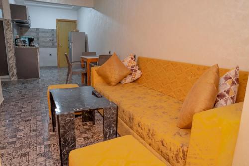 a living room with a yellow couch and a table at Lilia Quest in Dakhla