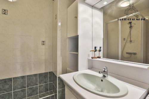 une salle de bain blanche avec un lavabo et un miroir dans l'établissement Ancora3 Appartement vue mer et place de parking, à Les Sables-dʼOlonne