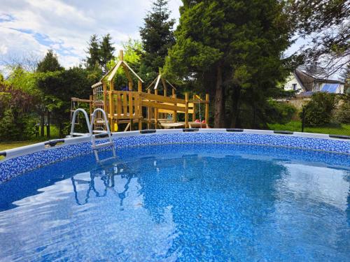 a large swimming pool with a playground in a yard at Family Rooms in Zabrze