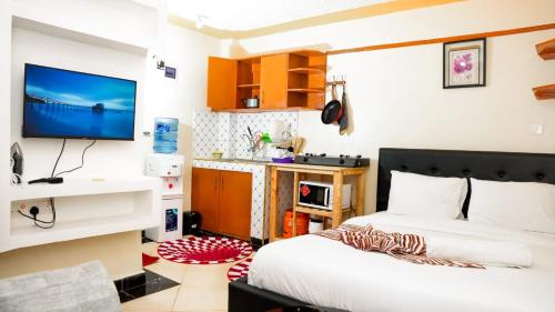 um quarto com uma cama e uma televisão na parede em Nelly fully furnished studios em Naivasha