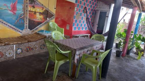 a table and chairs in a room with a wall at POUSADA ATINS MELo in Atins