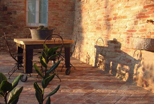 a table and a bench next to a brick wall at Castello di Granarola Relais - Adults Friendly - in Gradara