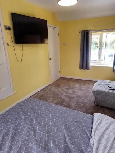 a bedroom with a bed and a flat screen tv on the wall at ACCOMADATION WREXHAM in Wrexham