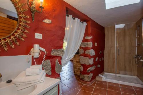 a bathroom with a red wall with a shower and a sink at Finca Casas Nanitas in Moya