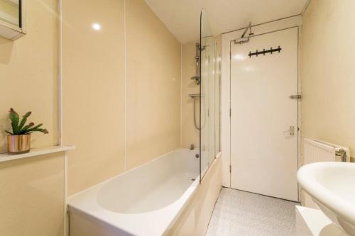 La salle de bains est pourvue d'une baignoire, d'un lavabo et d'une douche. dans l'établissement Edinburgh Morrison Central ApartHotel, à Édimbourg
