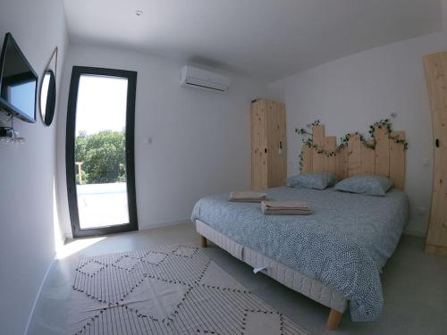 une chambre avec un lit et une grande fenêtre dans l'établissement Villa camille piscine chauffée proche pont d'arc, à Saint Alban Auriolles