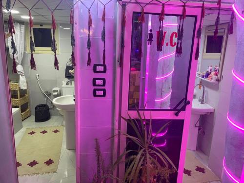 peace garden hostel & camp في الأقصر: آلة وردية في الحمام مع أضواء وردية
