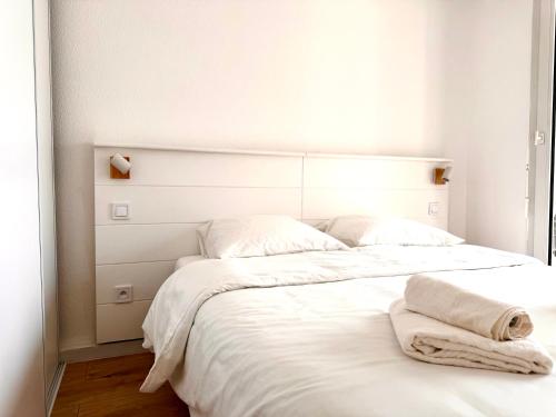 Una cama blanca con dos toallas encima. en Bellissimo Appartamento Vistamare, en Antibes