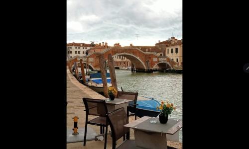 a table and chairs next to a river with a bridge at Villa Nadia in Dolo