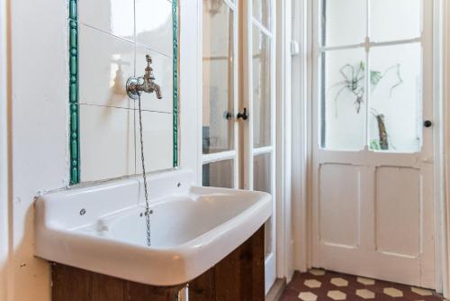 een badkamer met een witte wastafel en een deur bij GuestReady - Mola Green in Porto