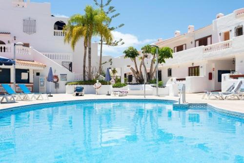 a swimming pool with chairs and a building at Sea view apartment in Los Cristianos in Arona