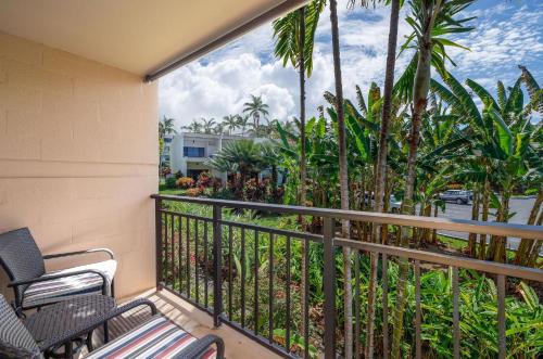 a balcony with chairs and palm trees at Kona Makai 3-203 in Kailua-Kona