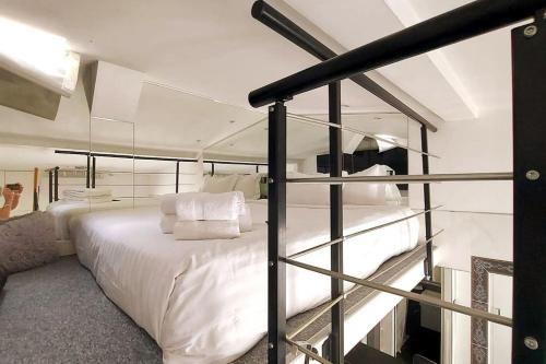 パリにあるDuplex Nôtre-Dame de Parisの白いベッドとガラスの壁が備わるベッドルーム1室が備わります。