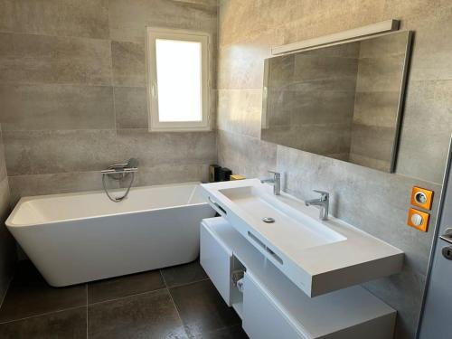 ein Badezimmer mit einer weißen Badewanne und einem Waschbecken in der Unterkunft Belle Villa, piscine chauffée à 250m des plages in Biarritz