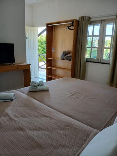 a bedroom with a large bed with two slippers on it at Milano Hotel Pousada Canoa Quebrada in Canoa Quebrada