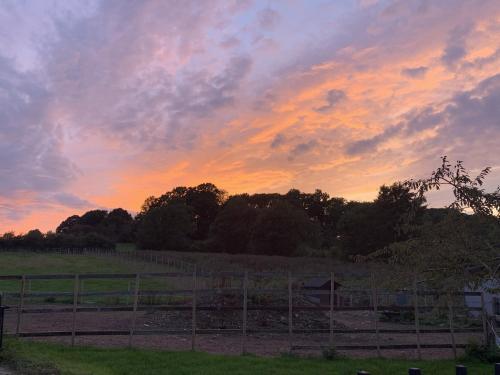 a sunset in a field with a fence and trees at The Farm Barn in Shepshed