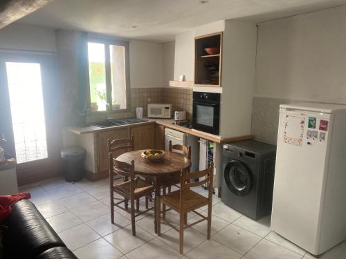 une cuisine avec une table, des chaises et un réfrigérateur dans l'établissement Maison Gallus, à Gallargues-le-Montueux