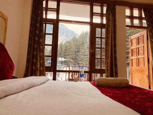 1 dormitorio con cama y ventana con vistas a la montaña en kalungi Royal INN, en Tenkāsi