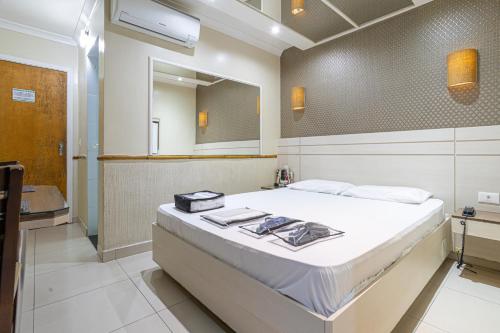 1 dormitorio con 1 cama grande y espejo en Hotel Coqueiros, en Carapicuíba