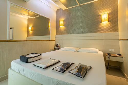 1 dormitorio con cama blanca y espejo en Hotel Coqueiros, en Carapicuíba