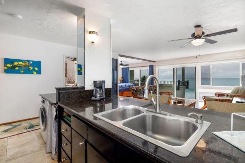 a kitchen with a sink and a living room at Banyan Tree 404D in Kailua-Kona